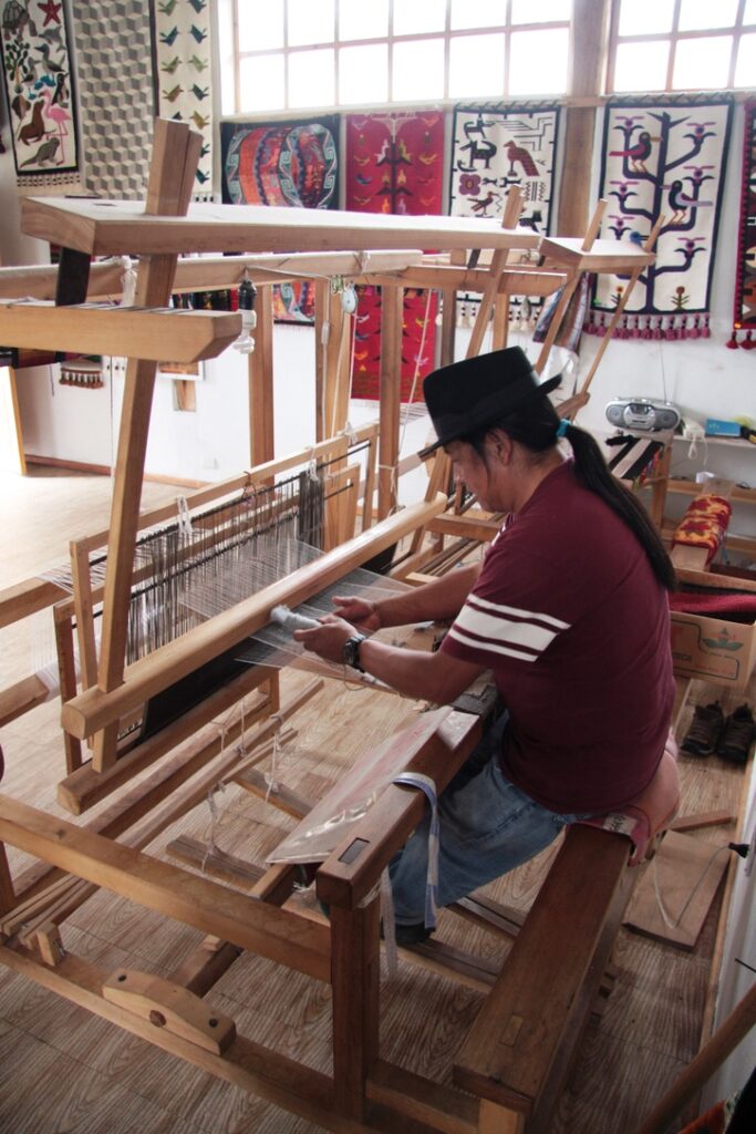 Close up of the weaver at his “oldtime" weaving equipment, made of would.