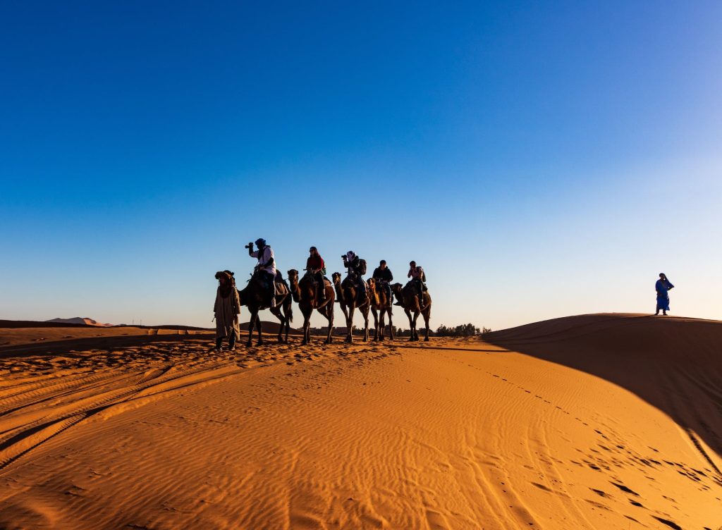 people riding on camels Impressions of the southern desert of Morocco (photo by Tomáš Malík on Pexels.com).