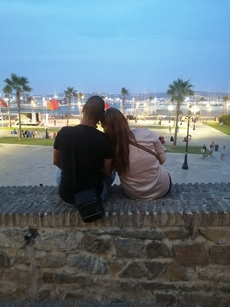 Daughter & boyfriend sitting on a fortress wall, overlooking the port of Tangier.