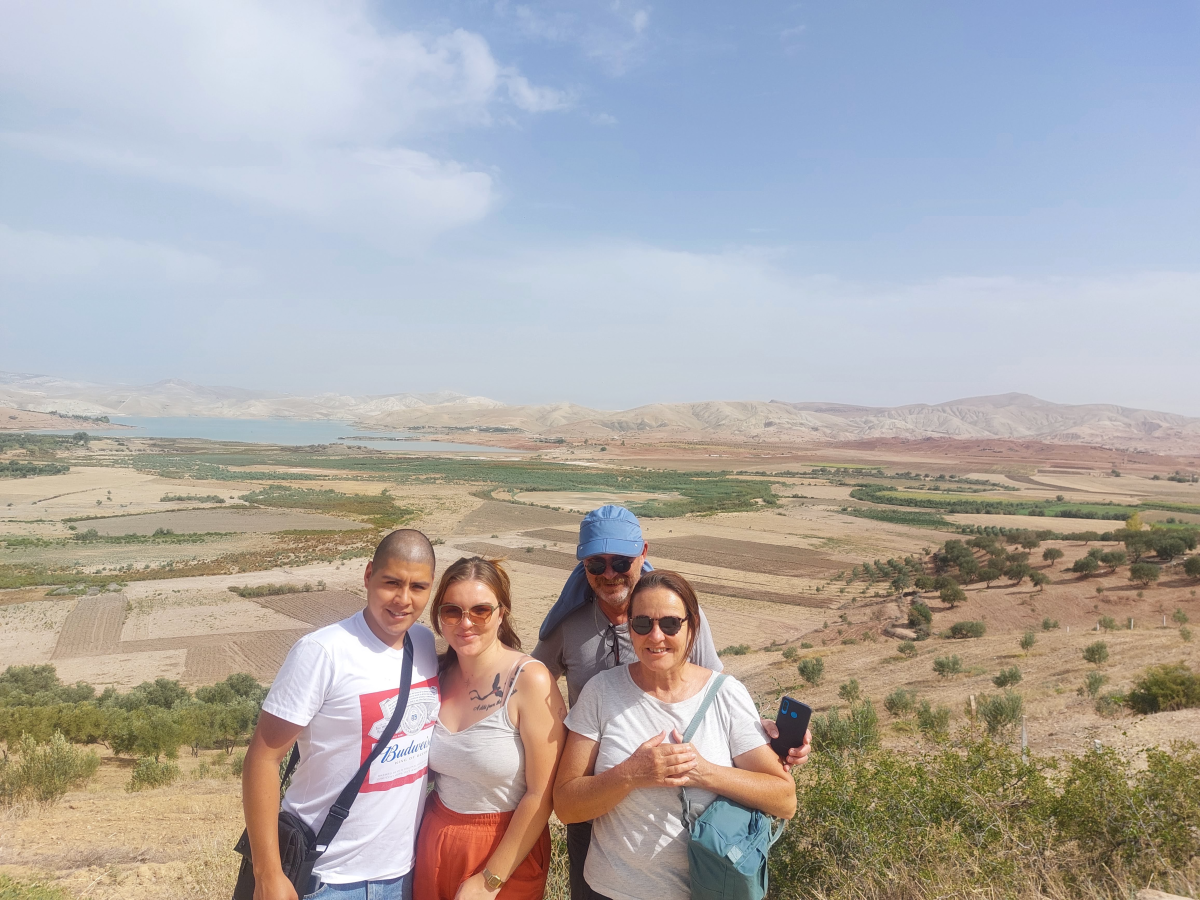 The four us posing in front of a dry Moroccan landscape Morocco. In the background the lake & dam of Sidi Chahed.