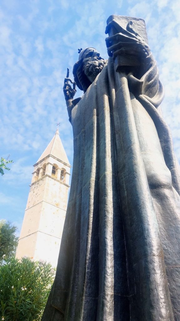 The Statue of Gregory of Nin. In the background the bell tower of the St. Arnir, last remains of a former Benedictine monastery, devastated by a fire in 1888.