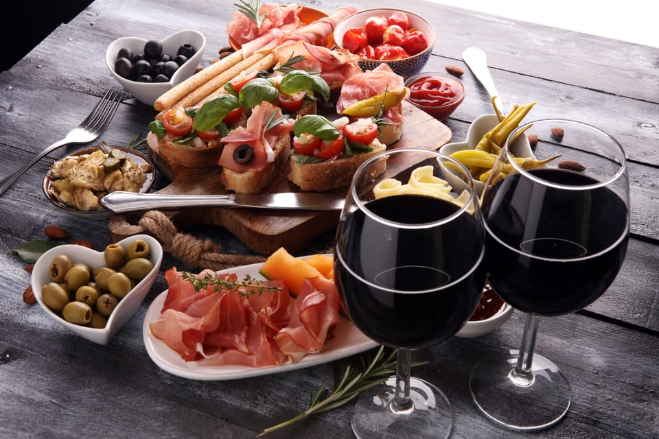 Impression of the food you can enjoy during a historical culinary trip near Šibenik. Olives, ham, cheese, olives, peppers, red wine & more.